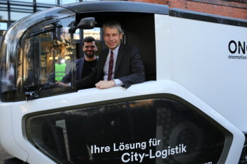 Staatssekretär Steffen Bilger nimmt in einem Cargobike Platz.